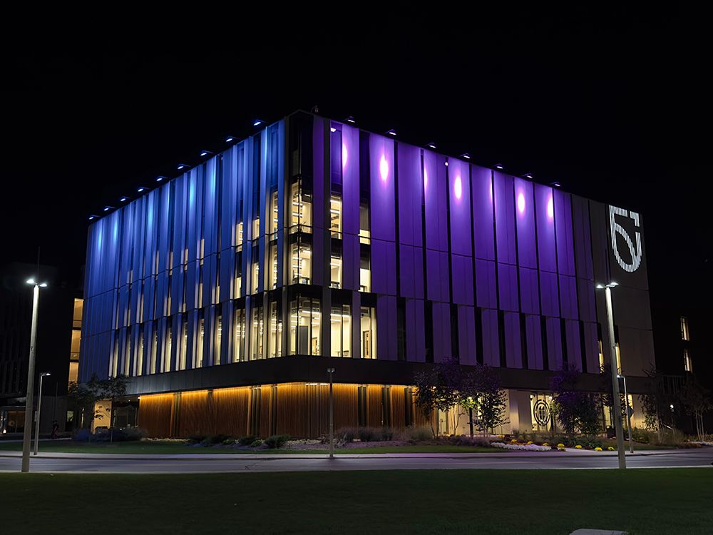 SHA Building lit up at night with blue and purple lights in support for DEAM